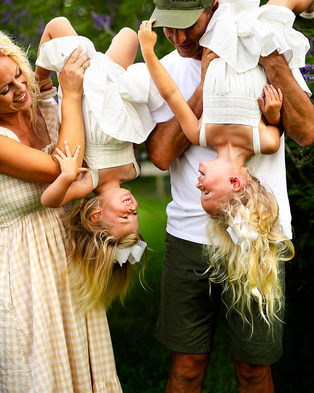 Mom and dad swinging their two girls upside down, everyone laughing