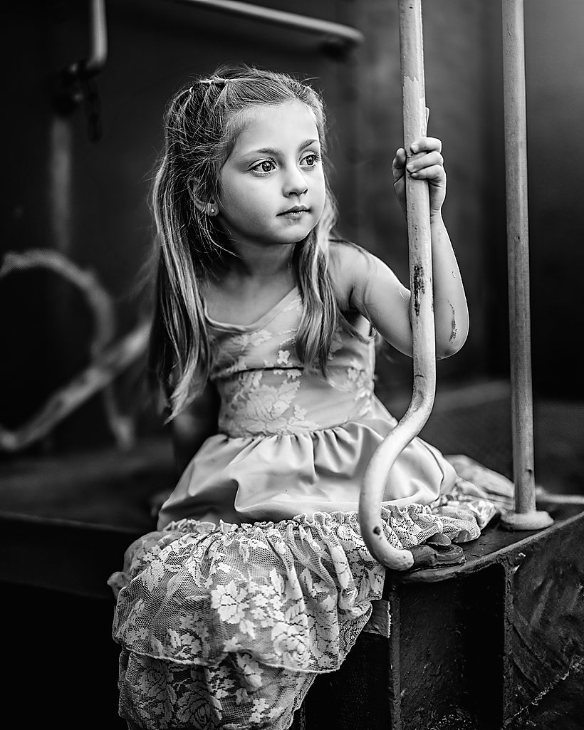 A little girl on an old carriage, in black and white